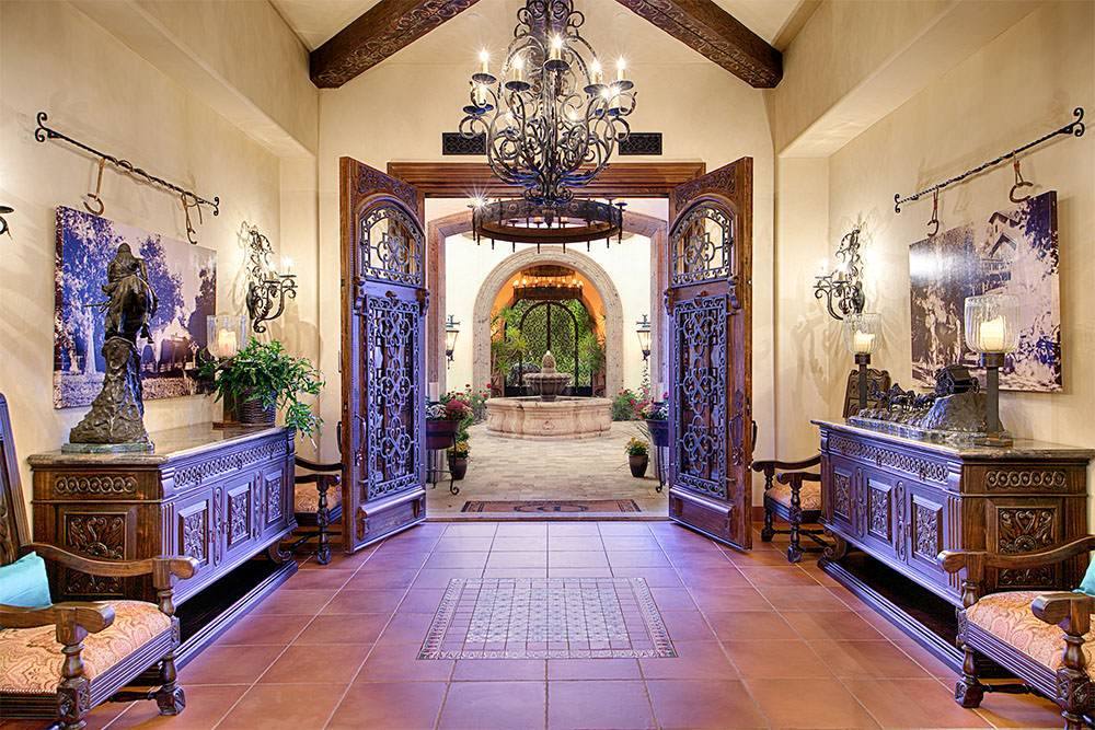 Formal entry hall with wrought iron chandelier and carved doors